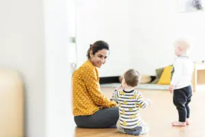 Smiling educator sitting beside children