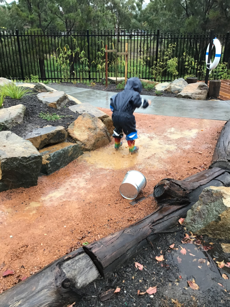Child in gumboots playing in the rain
